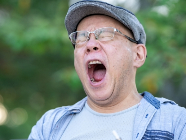 欠伸をする中年男性