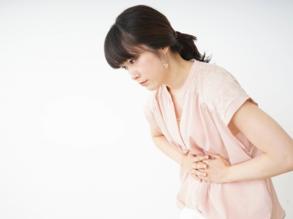 お腹を押さえる女性のイメージ画像