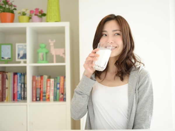 おやつに牛乳を飲む女性のイメージ画像