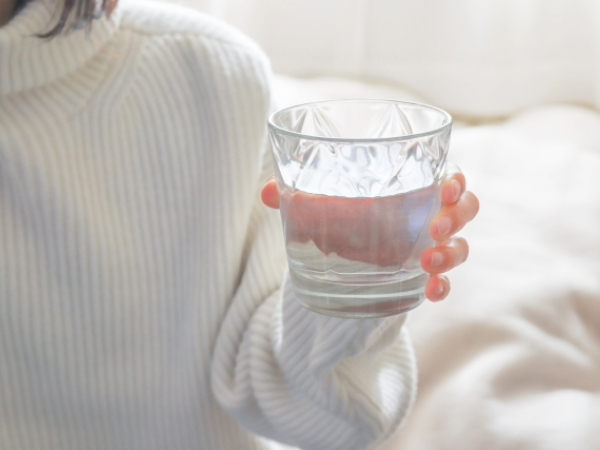 水の入ったコップを持つ女性のイメージ画像