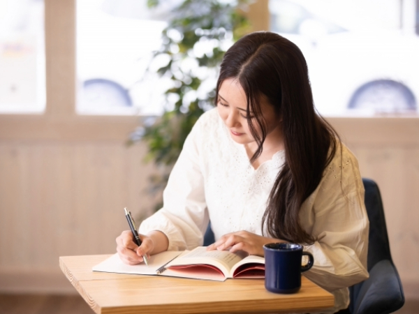 手帳に書き込みをする女性のイメージ画像