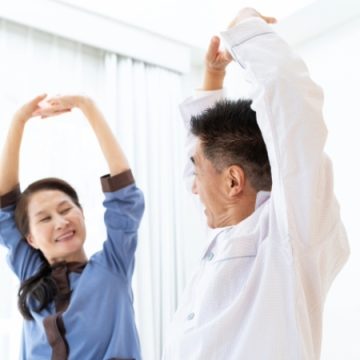 室内でストレッチをするシニア夫婦のイメージ画像