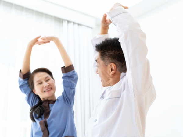 室内でストレッチをするシニア夫婦のイメージ画像