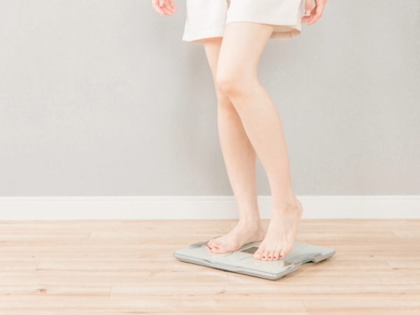 体重計に乗る細い脚の女性のイメージ画像
