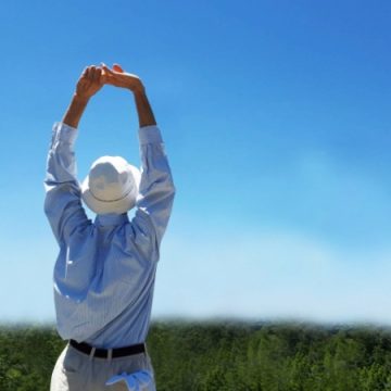 青空のもとストレッチをするシニア男性のイメージ画像