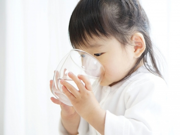 コップで水を飲む小さな女の子のイメージ画像