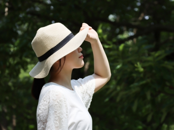 白い服と帽子をかぶって暑さを防ぐ女性のイメージ画像