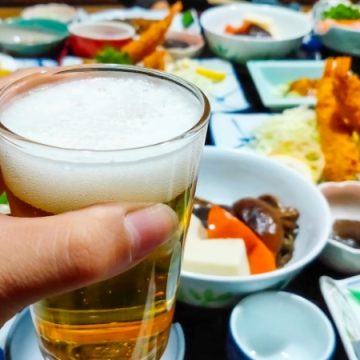 美味しそうな食事を目の前に、ビールで乾杯するイメージ画像