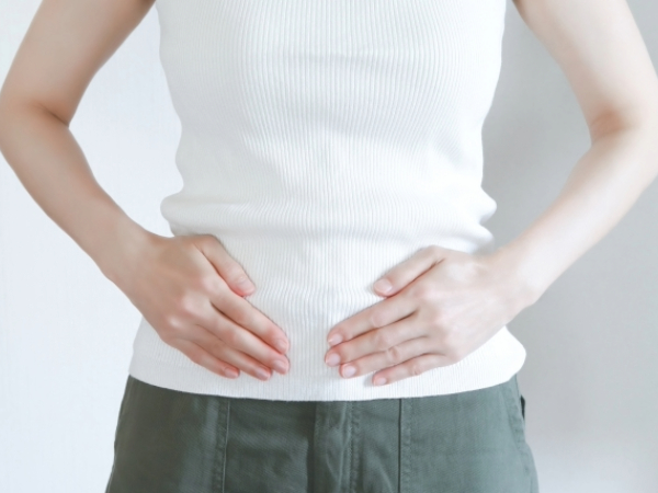 お腹をおさえる女性のイメージ画像