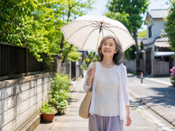日傘をさして歩いているシニア女性のイメージ画像