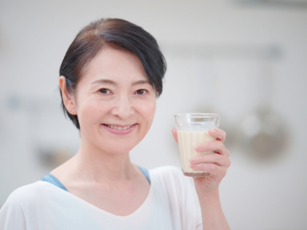 豆乳を飲もうとしているシニア女性のイメージ画像