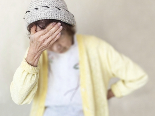 おでこに手を当てるシニア女性のイメージ画像