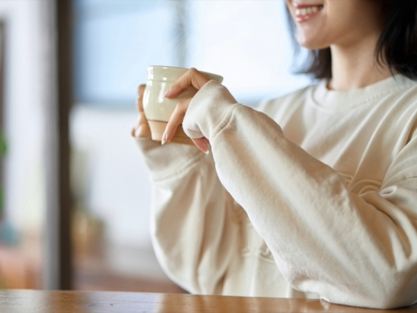 冬の朝に温かい飲み物を飲む女性のイメージ画像