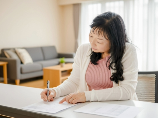 ノートを記入するシニア女性のイメージ画像