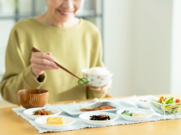 品数の多い朝食を食べるシニア女性のイメージ画像