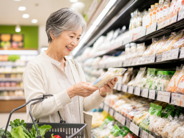 スーパーで食品を選んでいるシニア女性のイメージ画像